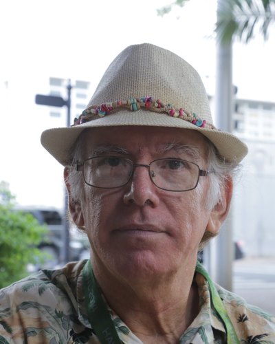 Portrait of William Braddock, founder of Little Red Apple Productions, wearing a straw hat and glasses.